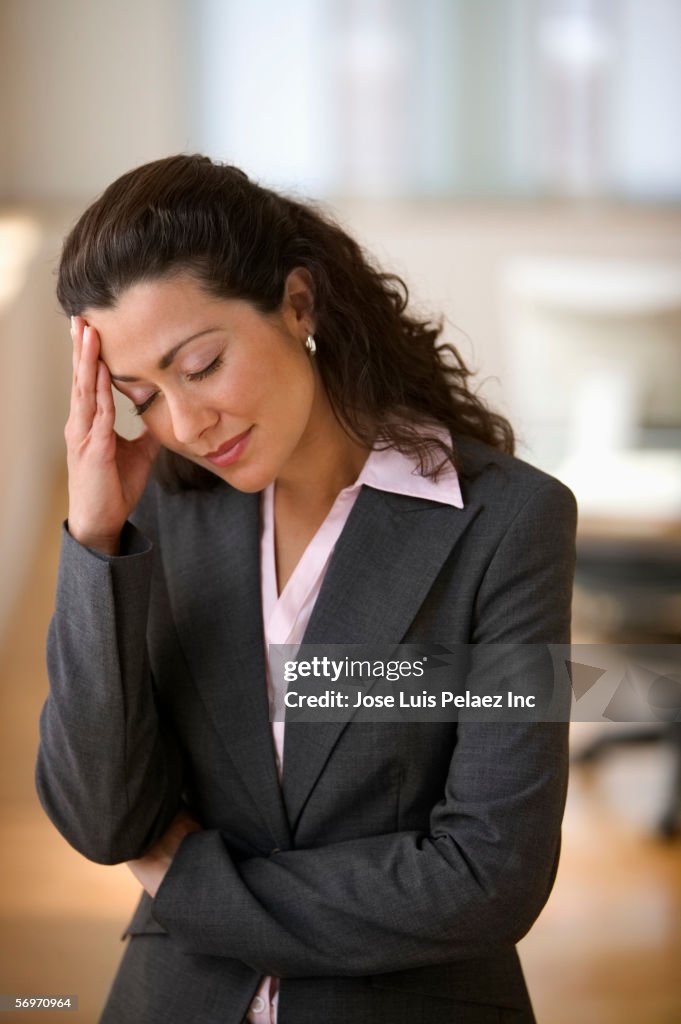 Businesswoman standing with headache