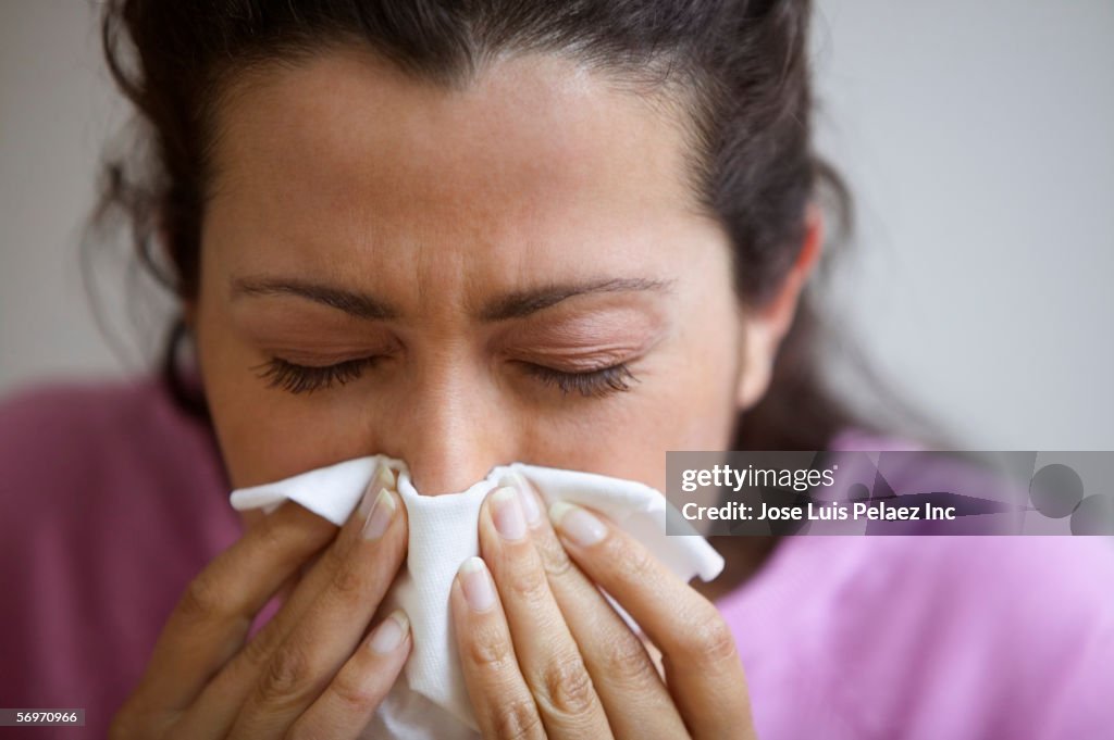 Close up of woman blowing nose
