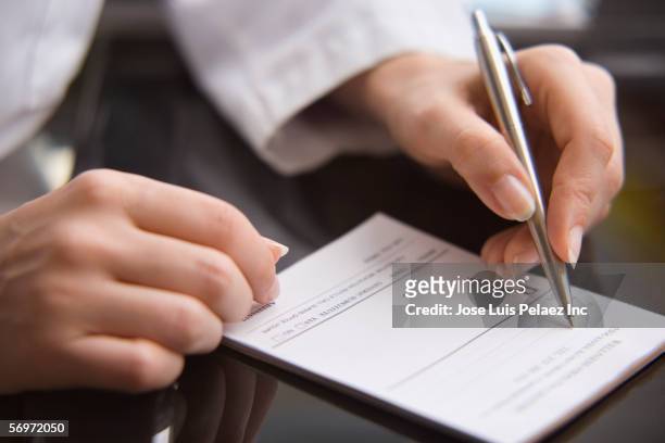 close up of female doctor's hands writing prescription - prescription medicine stock pictures, royalty-free photos & images
