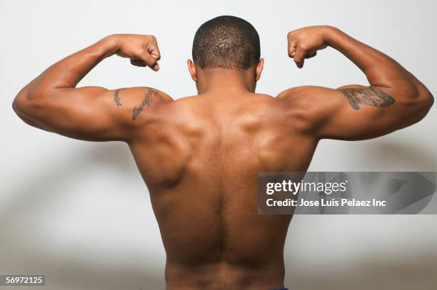 rear view of man's bare back flexing muscles - arm tattoos for black men fotografías e imágenes de stock