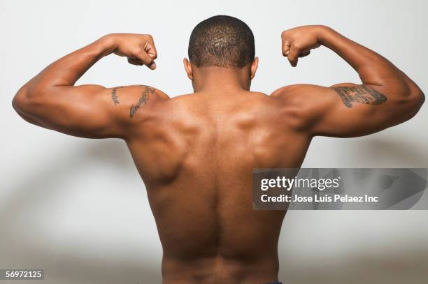rear view of man's bare back flexing muscles - posterior view of arm muscles stock pictures, royalty-free photos & images