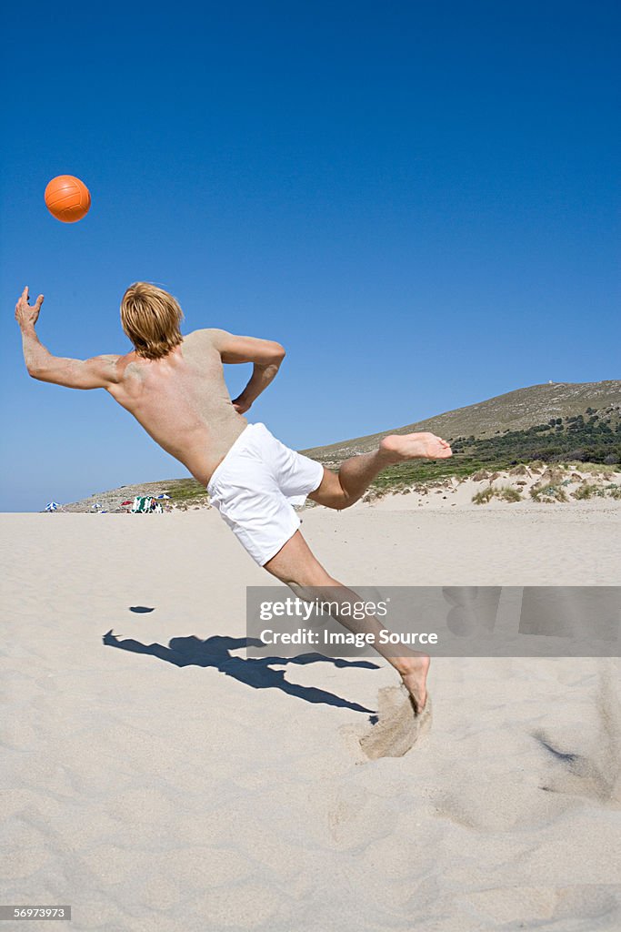 Hombre jugando con bola de juego en la playa