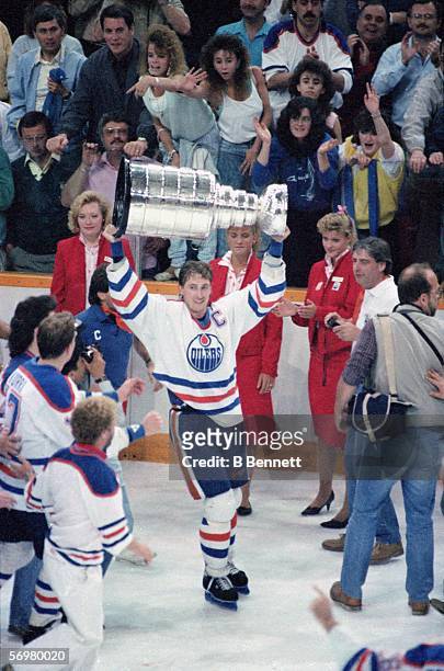 Canadian hockey player Wayne Gretzky of the Edmonton Oilers raises the Stanley Cup over his head in victory after the Oilers defeated the...