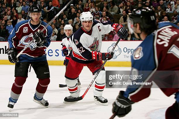 Adam Foote of the Columbus Blue Jackets defends against his former team as Joe Sakic and Alex Tanguay of the Colorado Avalanche control the puck as...