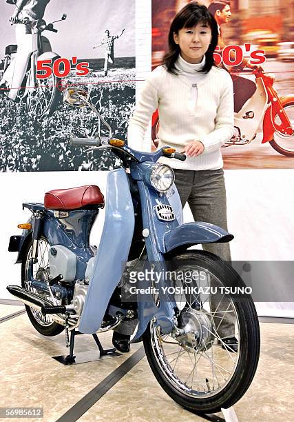 Japan's auto giant Honda Motor employee Makiko Yoshida displays the first generation model of the world's most popular motorcycle "Super Cup C100",...