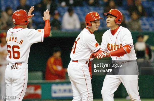 Chinese national team catcher Wang Wei is congratulated by teammates Zhang Hong-Bo and Chen Qi as Wang hit a two-run homer during the Asian round of...