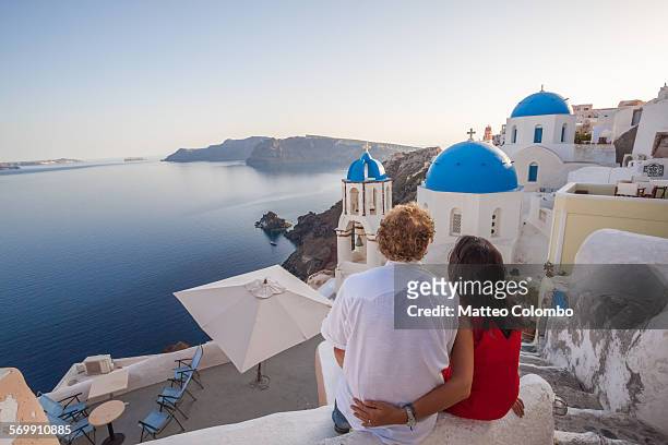 couple of tourists looking at sunset, santorini - greece foto e immagini stock
