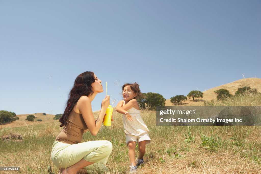 Mother and daughter blowing bubbles outside