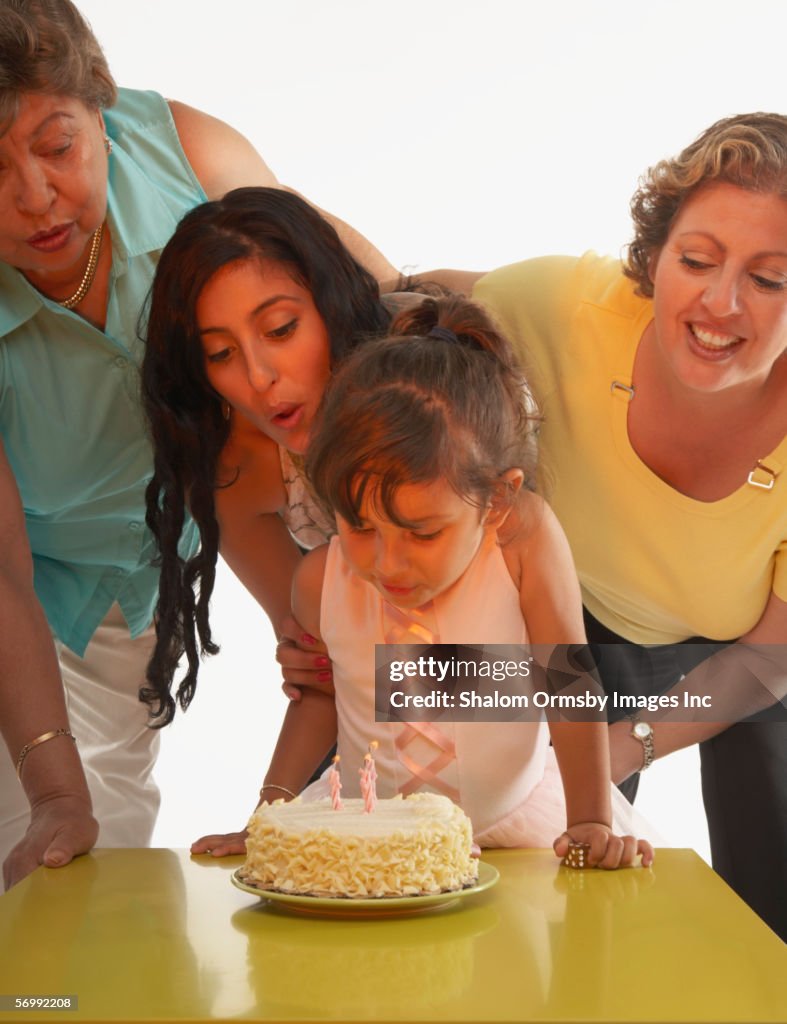 Young girl blowing out candles on her birthday cake