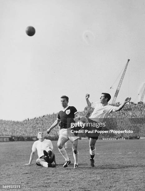 Tottenham Hotspur football player Cliff Jones beats Fulham players Alan Mullery and Jim Langley to the ball during a match at Fulham FC's ground...