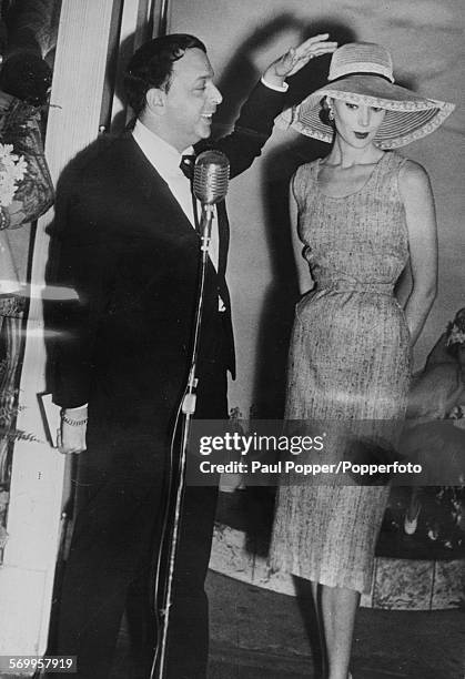 American milliner Mr John pictured with a female model wearing one of his new designs of hat with a very broad brim, January 20th 1953.