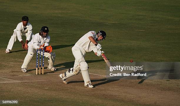 Alastair Cook of England hits out during his maiden test century as Wicketkeeper Mahendra Dhoni and Rahul Dravid look on during the day four of the...