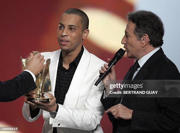 French singer Disiz La Peste gives a speech next to TV host Michel Drucker after winning the best hip-hop album of the year award during the 21st...