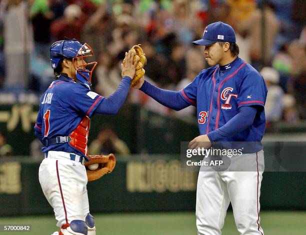 Taiwanese catcher Feng-Ming Chen and closing pitcher Hong-Chih Kuo "high-five" to celebrate their victory over China during the World Baseball...