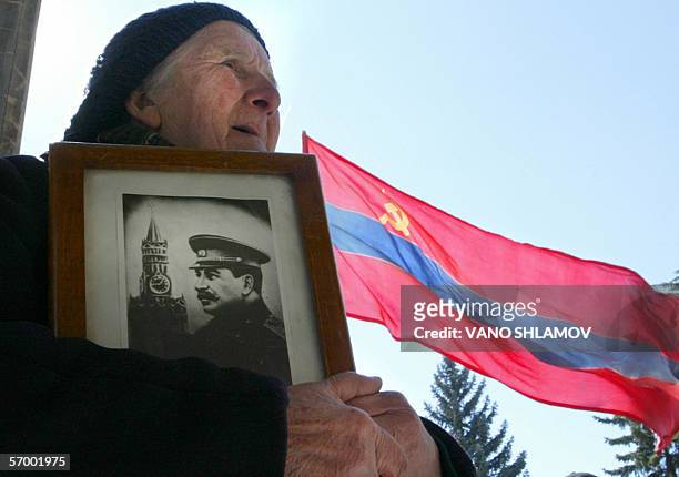 Georgian woman holds a portrait of former Soviet dictator Joseph Stalin commemorating the 53rd anniversary of his death in the Georgian town of Gori,...