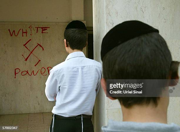 Jewish boys look at anti-semitic graffiti which was sprayed on the walls of a synagogue March 5, 2006 in Petah Tikva, near Tel Aviv, in central...