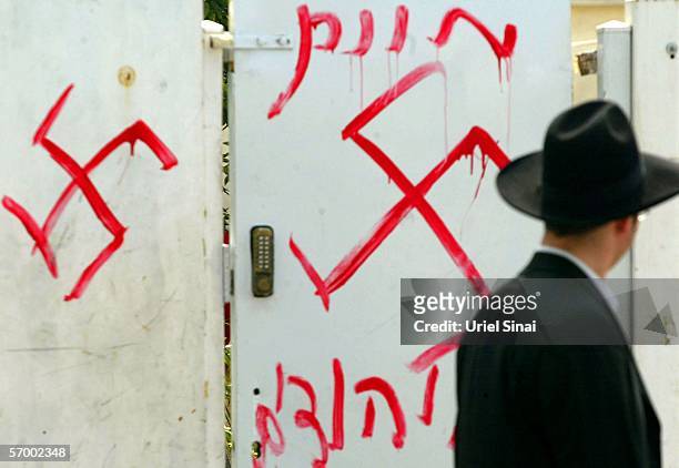 Jewish man looks at anti-semitic graffiti which was sprayed on the gate of a synagogue March 5, 2006 in Petah Tikva, near Tel Aviv, in central...
