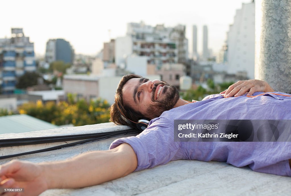 Man relaxing on rooftop, listening to music