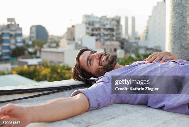 man relaxing on rooftop, listening to music - buenos aires rooftop stock pictures, royalty-free photos & images