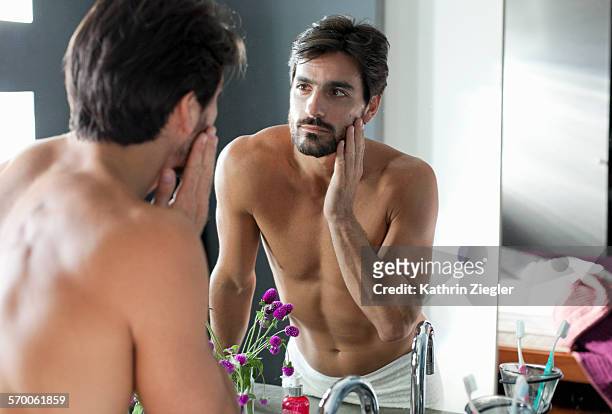 man looking at himself in bathroom mirror - black hair stockfoto's en -beelden