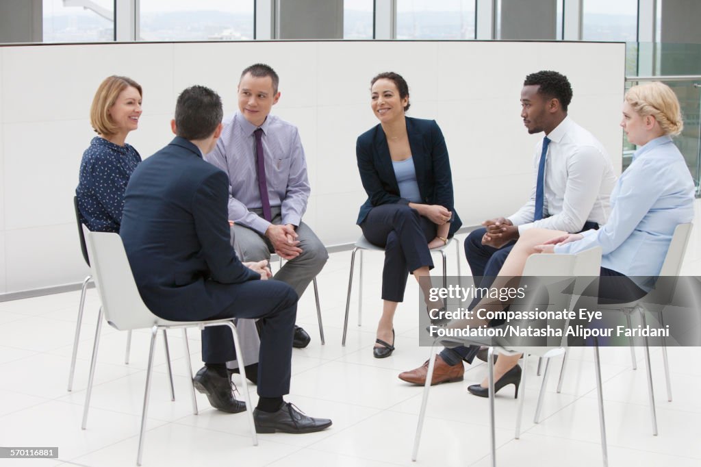 Business people in circle of chairs