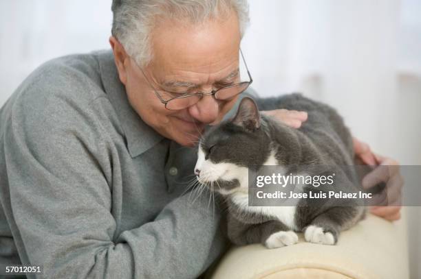 older man petting his cat - hispanic senior face stock-fotos und bilder