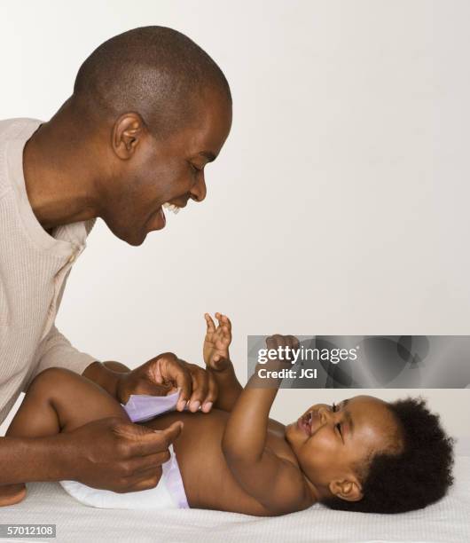 father changing his baby daughter's diaper - nappy change stockfoto's en -beelden