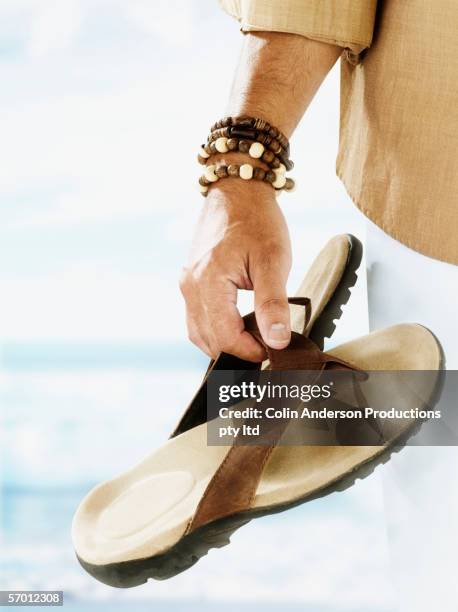 man carrying sandals on the beach - sandale stock-fotos und bilder