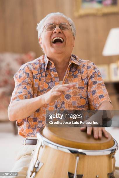 older man drumming on a bongo - playing drums stockfoto's en -beelden