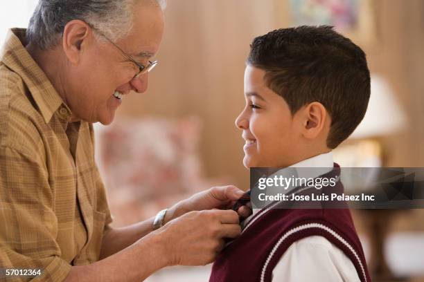older man tying grandson's school uniform tie - dominikanischer abstammung stock-fotos und bilder