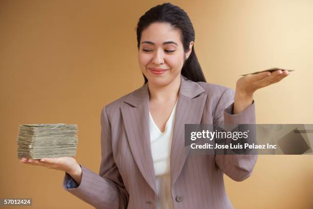 businesswoman holding uneven stacks of money in both hands - receiving cash stock pictures, royalty-free photos & images
