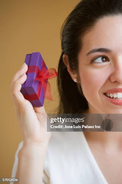 woman shaking small present to determine what it contains - shaking box stock pictures, royalty-free photos & images