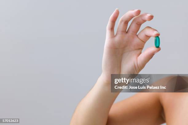 young woman holding a blue pill - finger tablet stock pictures, royalty-free photos & images