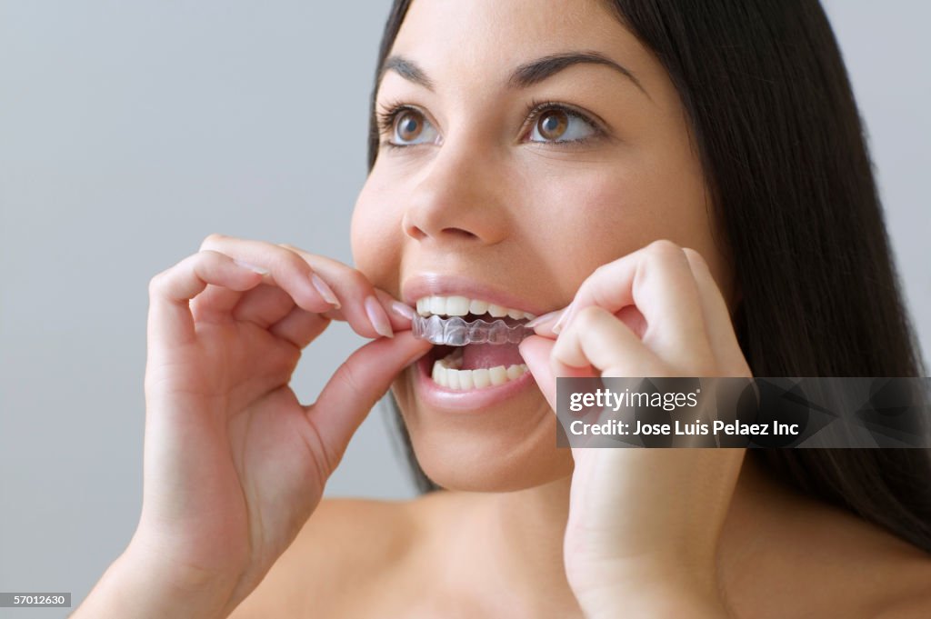 Young woman putting on invisible braces