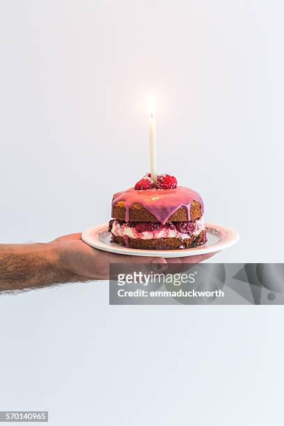 man's hand holding a victoria sponge birthday cake with a candle - birthday cake white background stock pictures, royalty-free photos & images