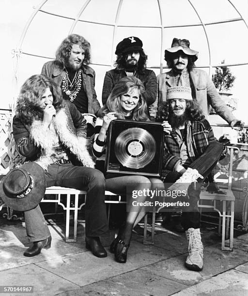 Portrait of English rock band Jethro Tull; Martin Barre, Jeffrey Hammond, Clive Bunker and John Evan and Ian Anderson, with actress Julie Ege holding...