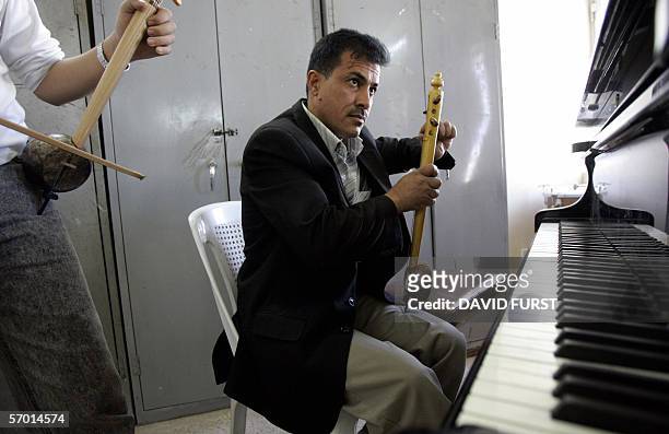 An Iraqi music teacher tunes an Joza, a native Iraqi instrument made from coconut shells, before class at the Iraqi school of Music and Ballet, in...