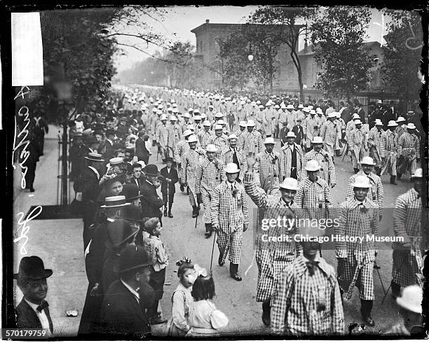 Image of meat cutters wearing checkered overcoats marching in a Labor Day parade in Chicago, Illinois, 1900s. Text on the negative reads: Meat...