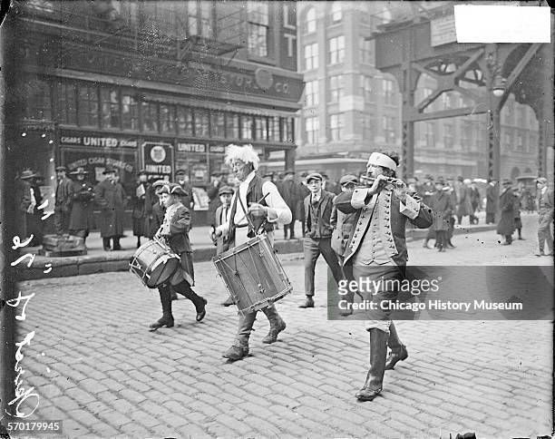 Image of men dressed in Colonial costumes, marching south and playing drums and a fife on Market Street in the Loop community area, Chicago,...
