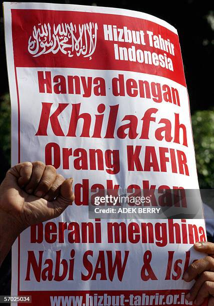 An Indonesian protestor from Hizbut Tahrir holds a banner reads, "Only the caliphate non-Islamic will have no brave to insulting Prophet Muhammad and...