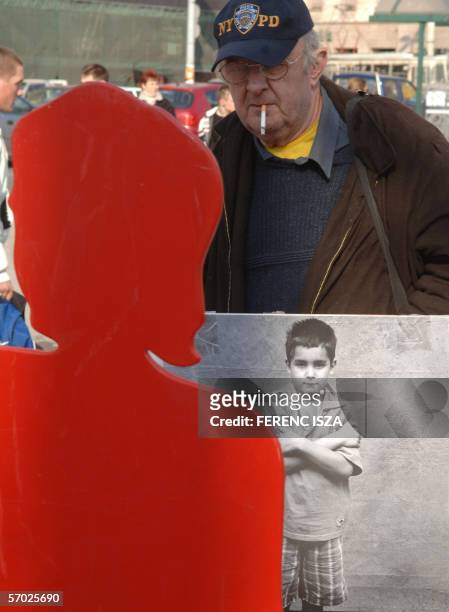 An man looks sporting a sandwich board, looks at a red cut-out of a woman 08 March 2006 as associations,Amnesty International, "NANE", women's rights...