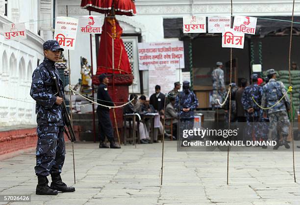 An armed Nepalese policeman stands guard in front of nearly empty lines set up for voters to queue at a polling station during the country's...