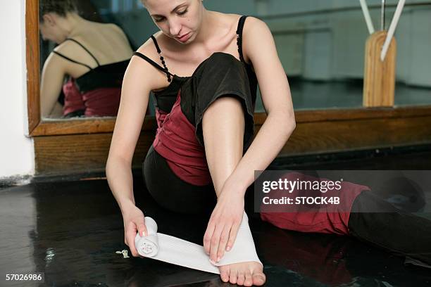 a female ballet dancer bandaging her feet - ballet feet hurt stock pictures, royalty-free photos & images