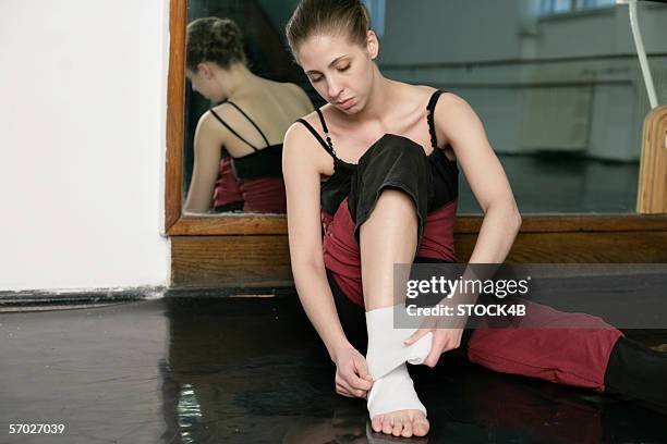 a female ballet dancer bandaging her feet - ballet feet hurt stock pictures, royalty-free photos & images