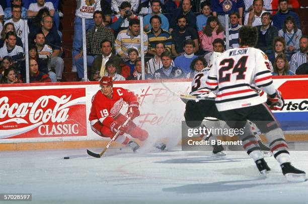 Canadian professional hockey player Steve Yzerman, center for the Detroit Red Wings, controls the puck while Canadian professional hockey players and...