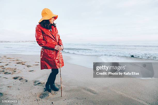 woman in rainclothes on the beach - oil skin stock pictures, royalty-free photos & images