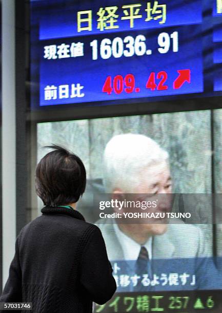 Pedestrian gazes at a share prices board showing governor Bank of Japan Toshihiko Fukui in Tokyo,+ 09 March 2006. Japanese share prices rose 409.42...