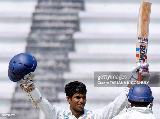 Sri Lankan cricketer Upul Tharanga raises his bat and helmet in the air after scoring a century during the second day of the second Test Match...