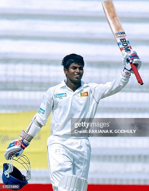 Sri Lankan cricketer Upul Tharanga raises his bat in the air to celebrate scoring a century during the second day of the second Test Match between...