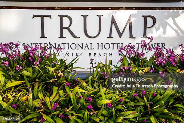 Tropical flowers and front entrance sign of Trump International Hotel Waikiki Beach. Five Star luxury hotel & residences owned by Donald Trump,...